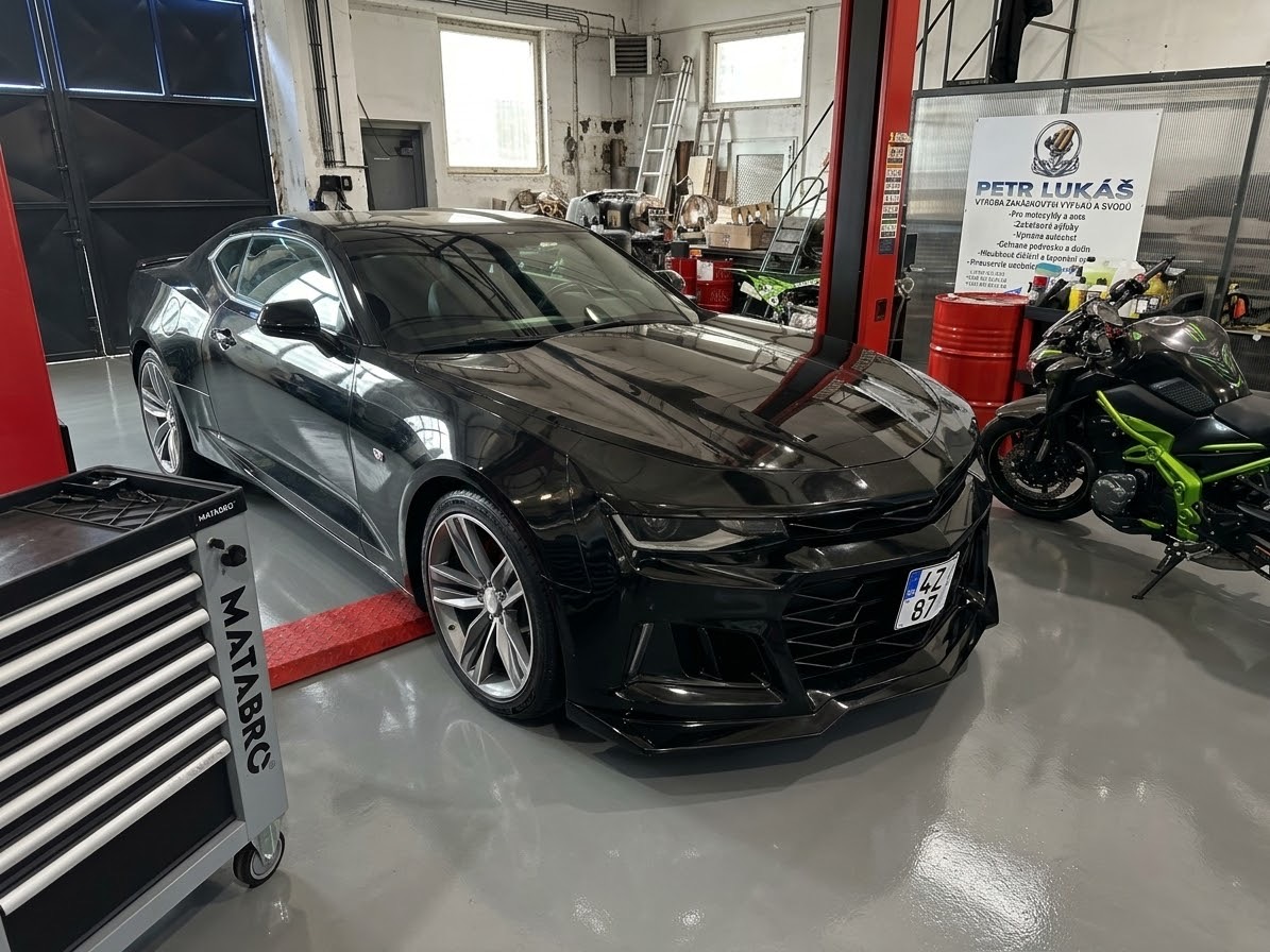Černý Chevrolet a motocykl v dílně P.A.L. Custom Garage