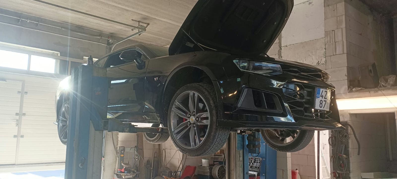 Černé auto na zvedáku při přezouvání